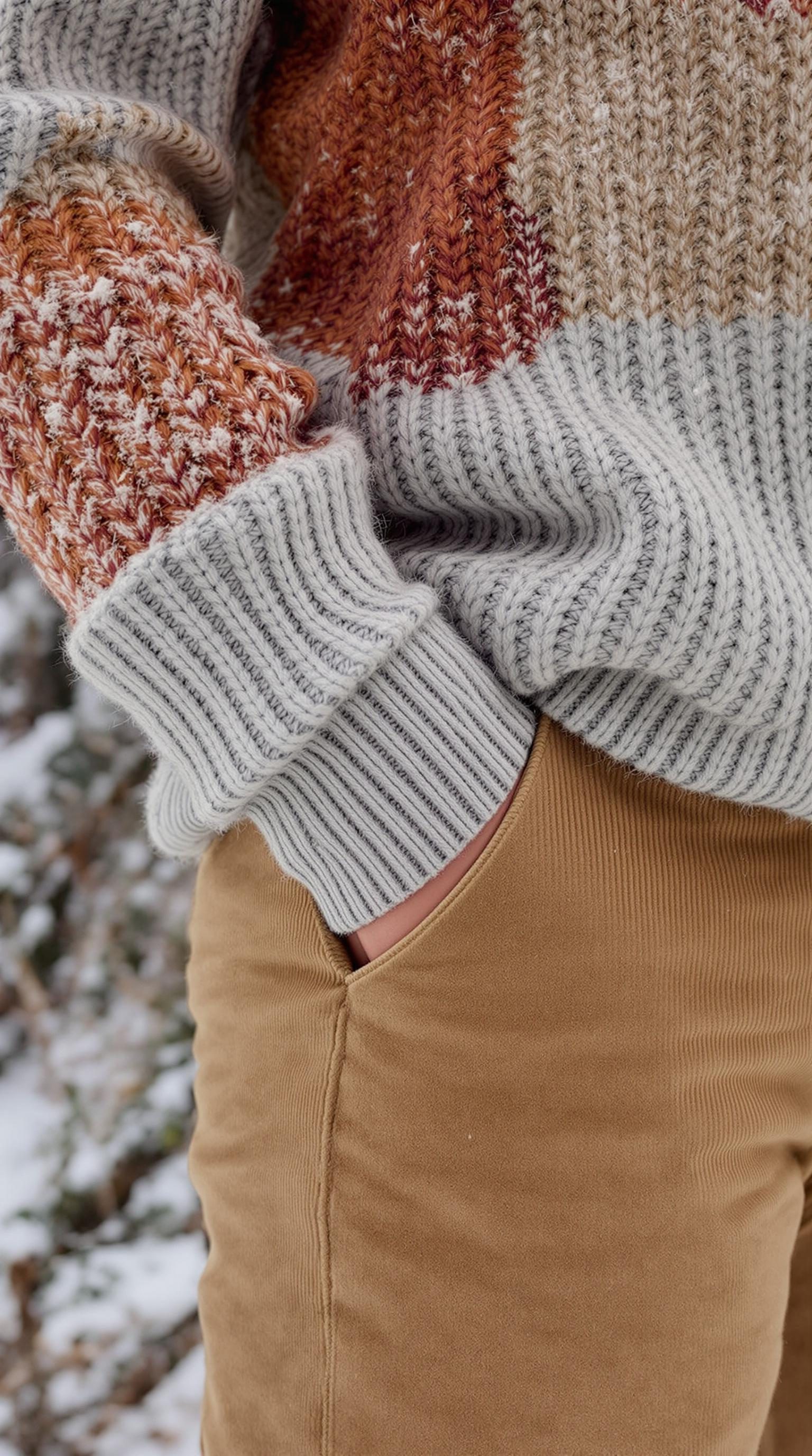 Close-up of a knitted wool sweater and corduroy pants in winter setting